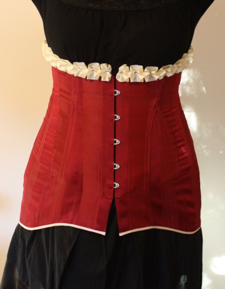 Front of red striped satin 1911 long line corset with cream satin trimmings and cream satin laces